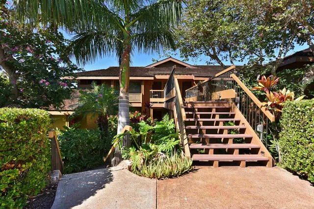 a view of a tall white house with a yard and potted plants