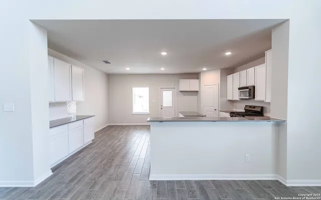 a large kitchen with granite countertop a large counter top space a sink stainless steel appliances and cabinets