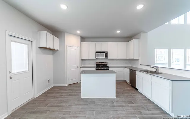 a kitchen with stainless steel appliances granite countertop a sink a stove a refrigerator cabinets and a window