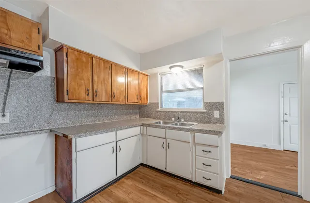 a kitchen with white cabinets and sink