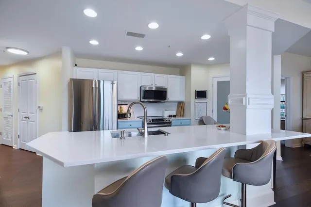 a kitchen with stainless steel appliances granite countertop a sink a stove a refrigerator cabinets and chairs