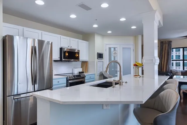 a kitchen with stainless steel appliances a refrigerator a stove a sink a dining table and chairs