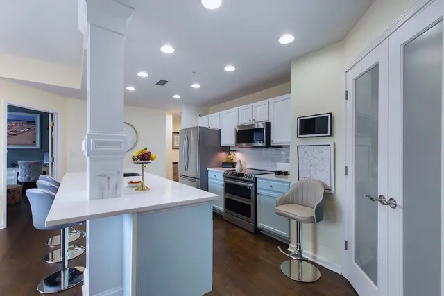 a kitchen with stainless steel appliances a sink a stove a refrigerator cabinets and chairs