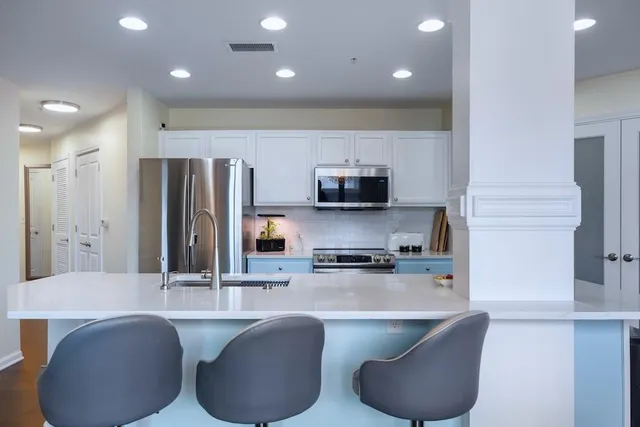 a kitchen with stainless steel appliances granite countertop a sink a stove and a refrigerator