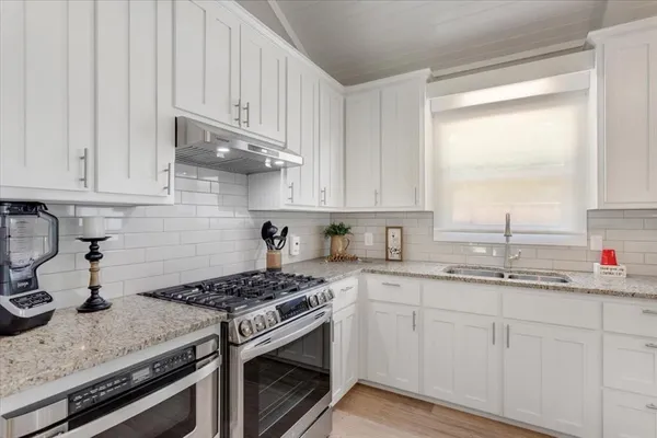 a kitchen with granite countertop a sink stove and cabinets