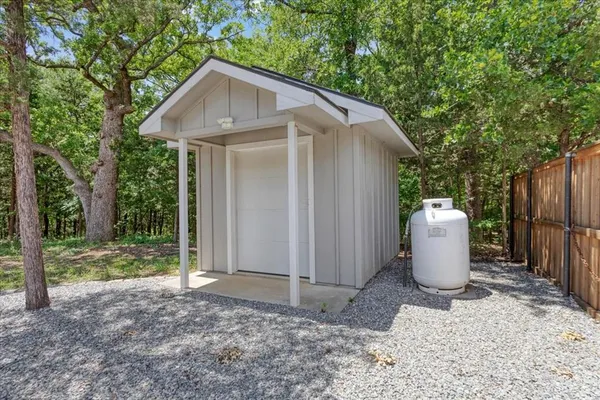 a view of a small house with potted plants and large tree