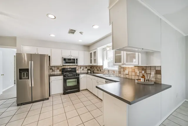 a kitchen with granite countertop white cabinets stainless steel appliances a sink and a window