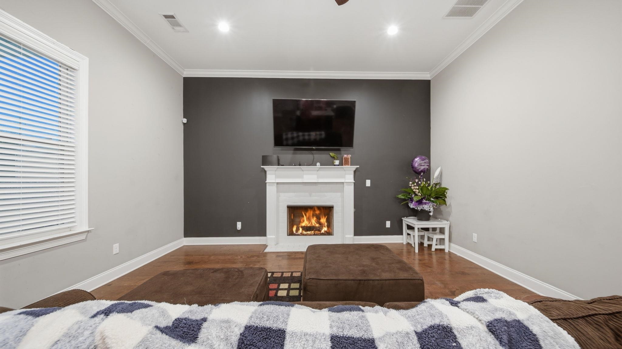 70 Trinity Cove Atoka, TN 38004 - Photo 5 of 25 Living area featuring a white fireplace with a dark accent wall, wood-finish flooring, white baseboards, and crown molding