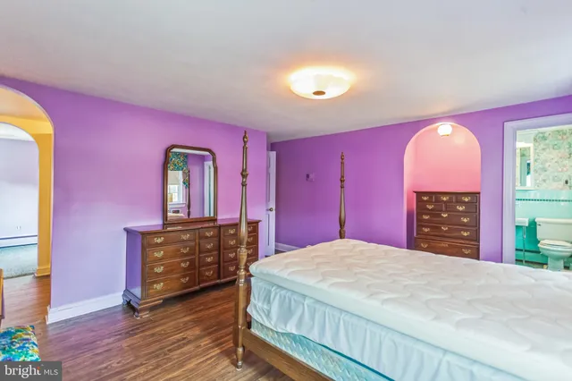 a spacious bedroom with a bed and a dresser with wooden floor