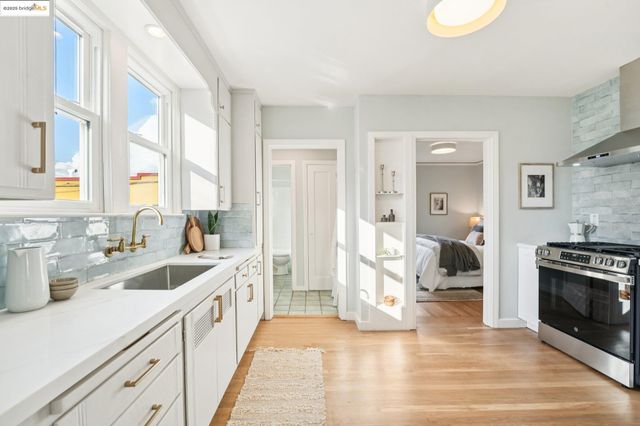 a kitchen with a sink dishwasher stove and white cabinets with wooden floor