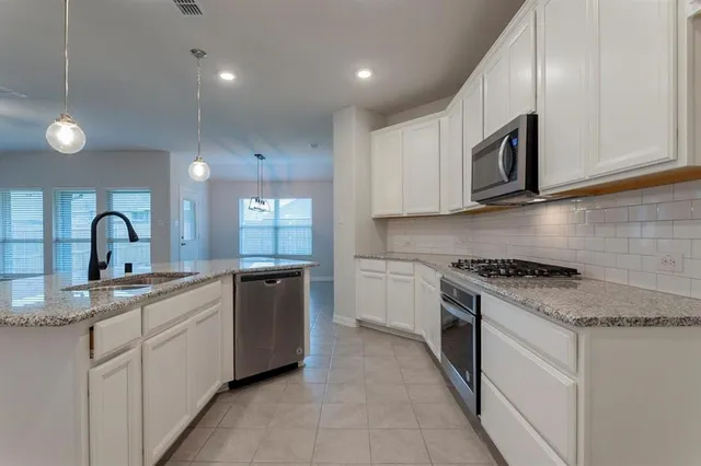 a kitchen with white cabinets and appliances