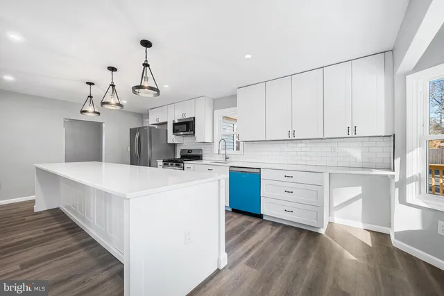 a kitchen that has a lot of cabinets in it and wooden floors