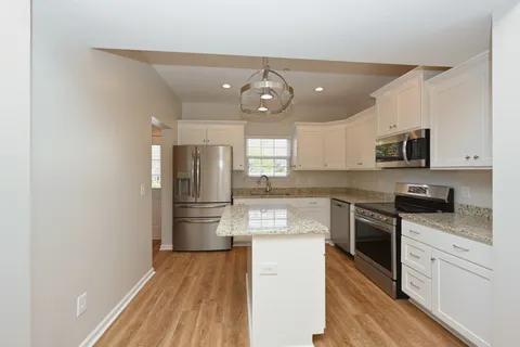 a kitchen with granite countertop stainless steel appliances a refrigerator stove and microwave