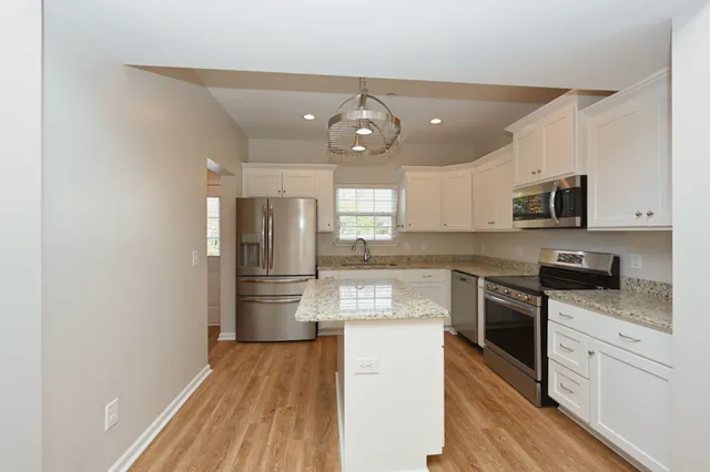 a kitchen with granite countertop stainless steel appliances a refrigerator stove and microwave