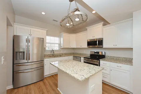 a kitchen with granite countertop white cabinets stainless steel appliances a sink and a window