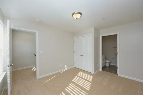 a view of an empty room with window and bathroom