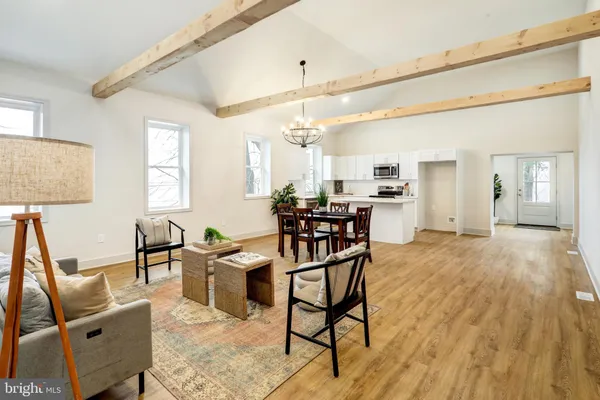 a view of a dining room and livingroom with furniture wooden floor a chandelier
