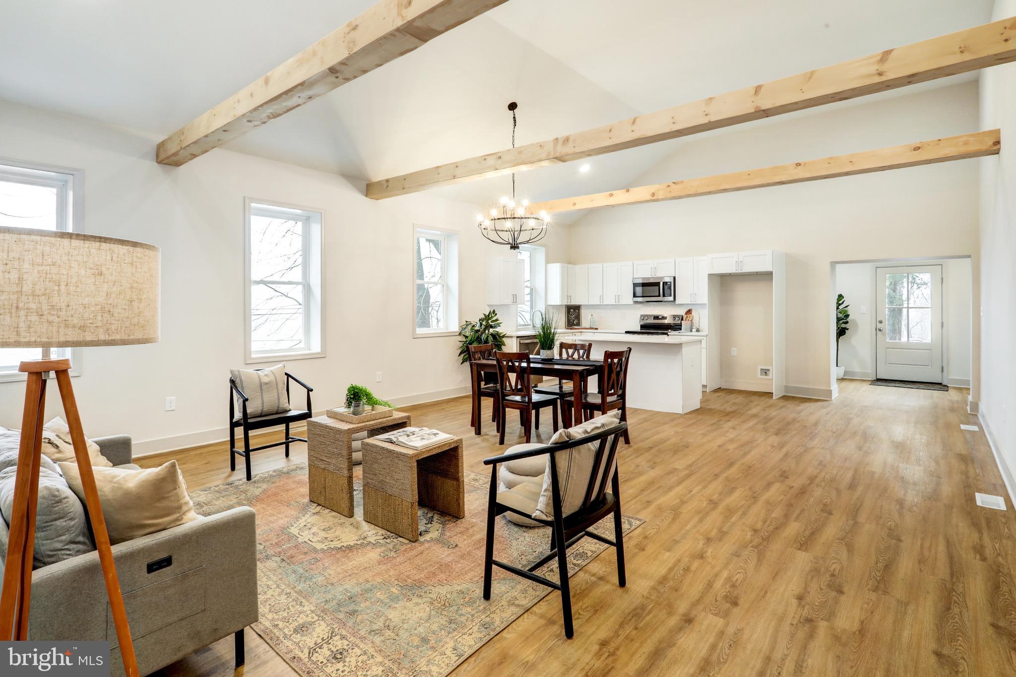 a view of a dining room and livingroom with furniture wooden floor a chandelier