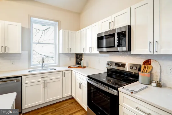 a kitchen with cabinets stainless steel appliances and wooden floor