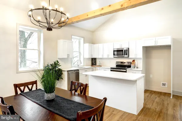 a kitchen with stainless steel appliances a dining table chairs a refrigerator and cabinets