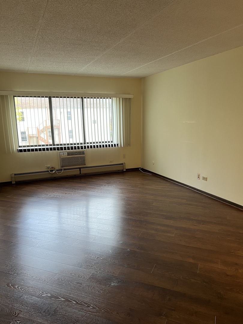 835 Pearson Street, Unit 209 Des Plaines, IL 60016 - Photo 4 of 10 a view of an empty room with wooden floor and a window