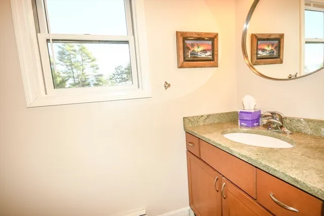 a bathroom with a granite countertop sink mirror and a window