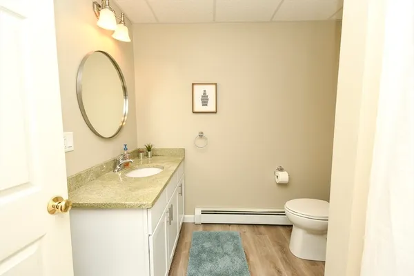 a bathroom with a granite countertop toilet sink and mirror