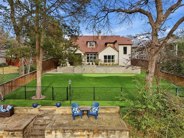 a view of a white house with a big yard and potted plants