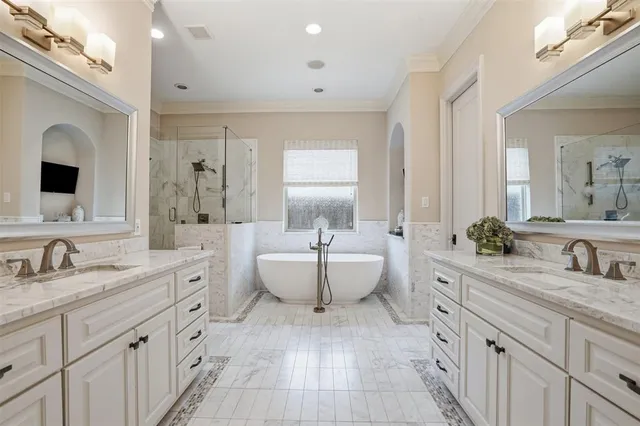 a spacious bathroom with double vanity a large mirror and a bathtub