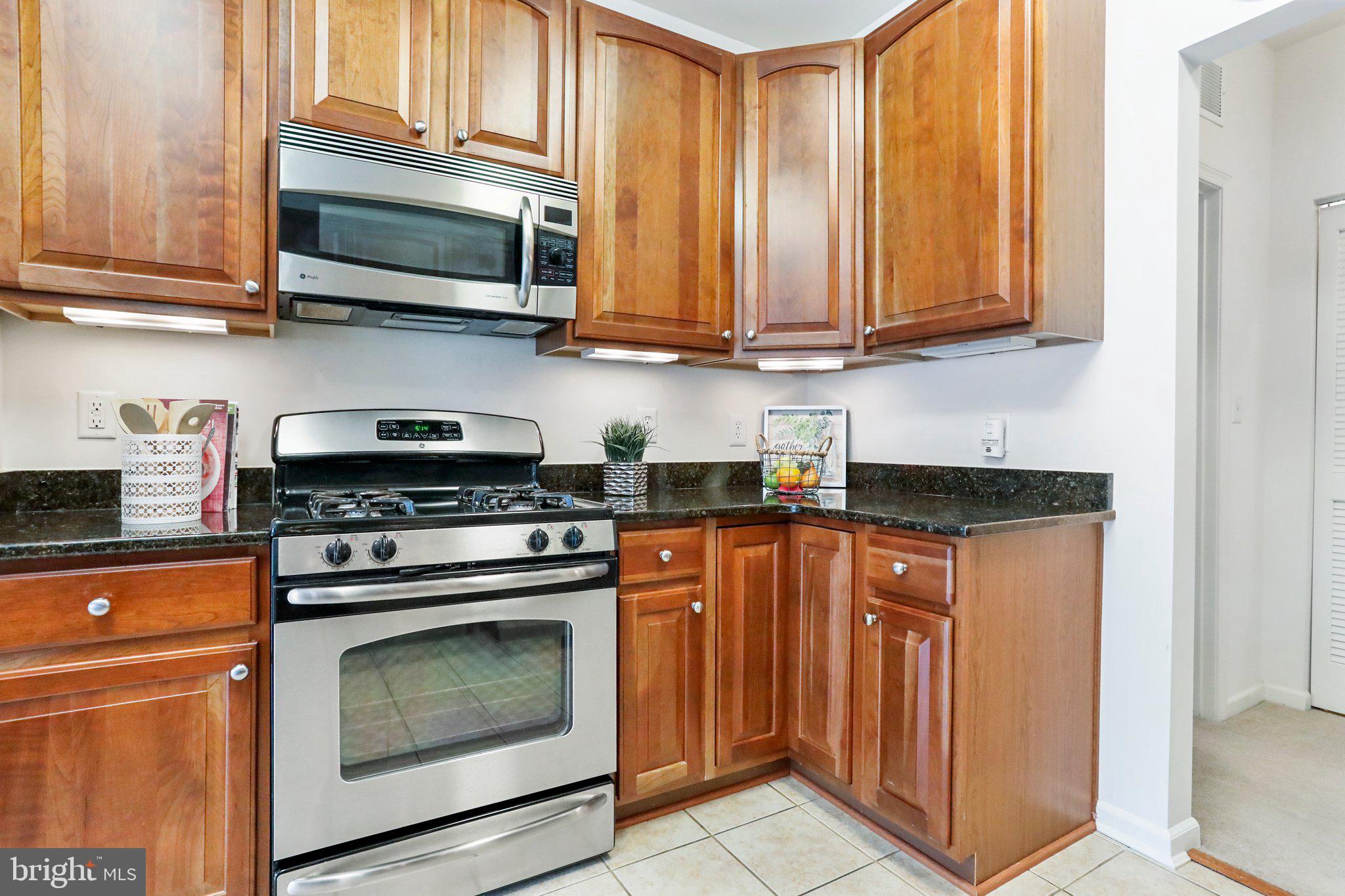 a kitchen with stainless steel appliances granite countertop wooden cabinets a stove top oven
