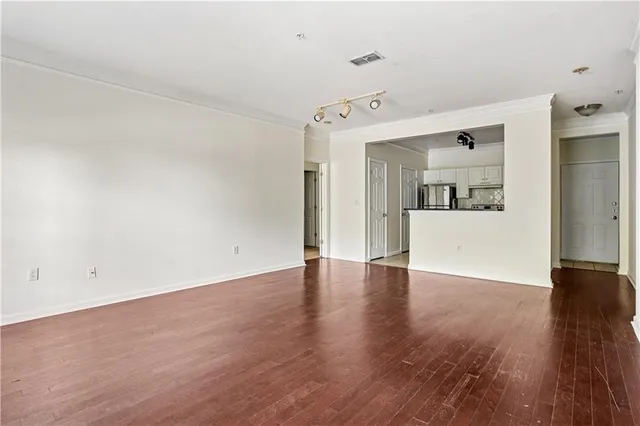 a view of a big room with wooden floor and kitchen view