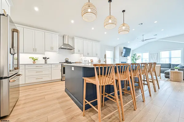 a kitchen with stainless steel appliances kitchen island granite countertop a table chairs and white cabinets