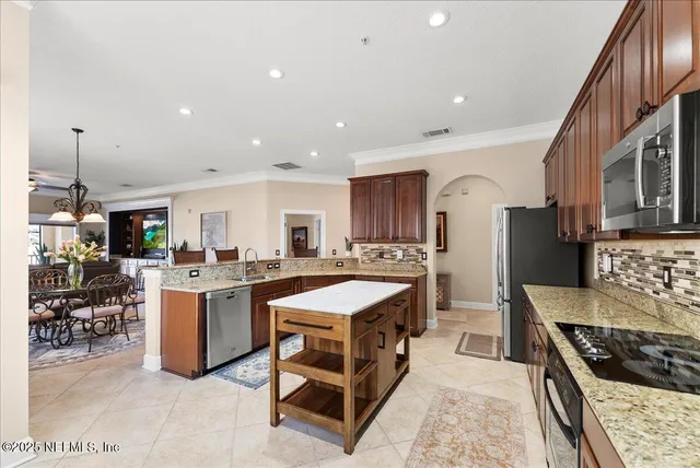 a kitchen with stainless steel appliances granite countertop a stove a sink dishwasher a refrigerator and a oven with wooden cabinets