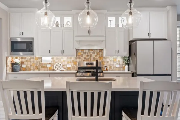 a kitchen with stainless steel appliances a stove a sink and white cabinets