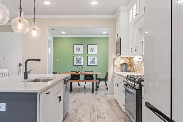 a kitchen with stainless steel appliances a kitchen island hardwood floor sink stove dining table and chairs