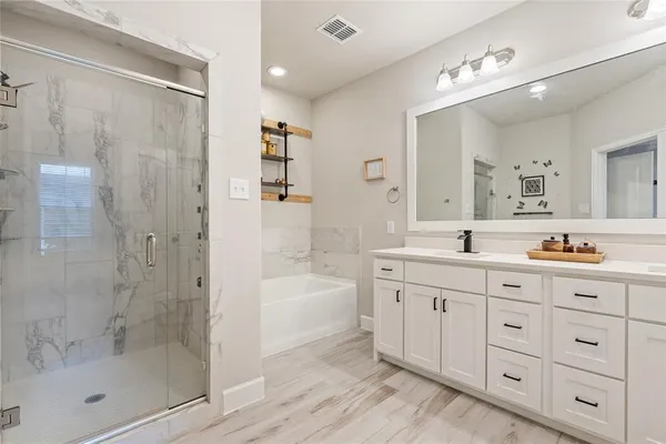 a spacious bathroom with a granite countertop tub sink a mirror a shower and vanity