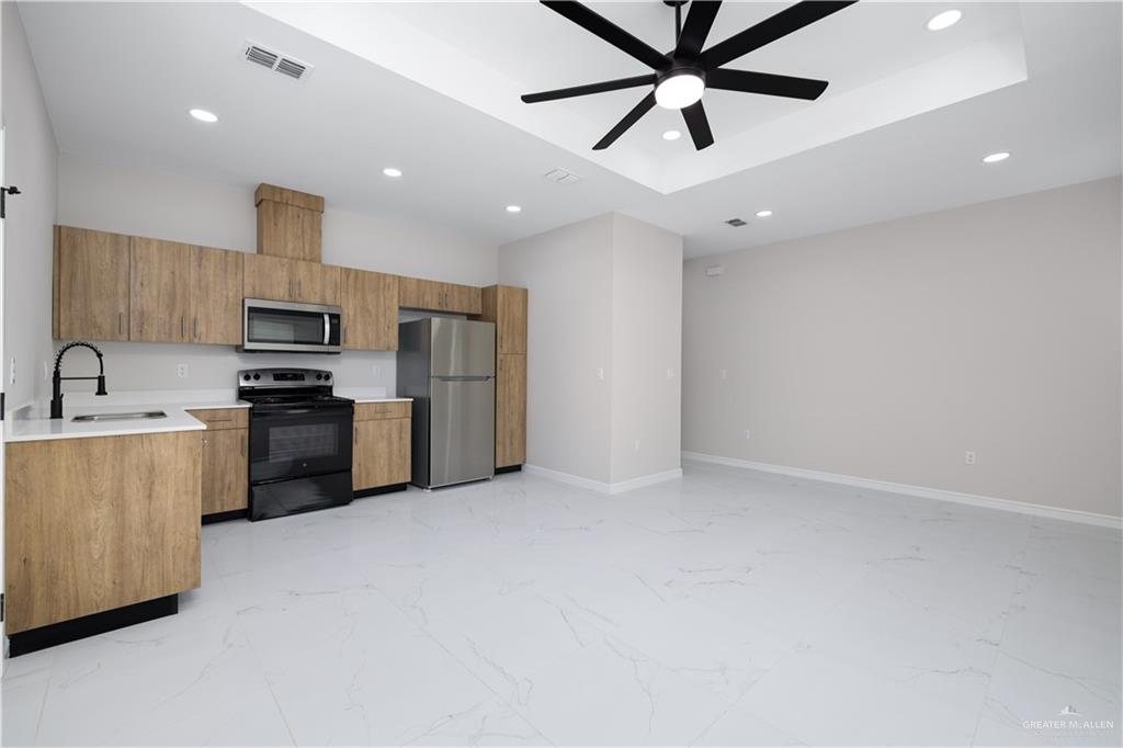 5335 Vision Street, Unit B Rio Grande City, TX 78582 - Photo 2 of 8 a kitchen with granite countertop a refrigerator oven a sink and white cabinets