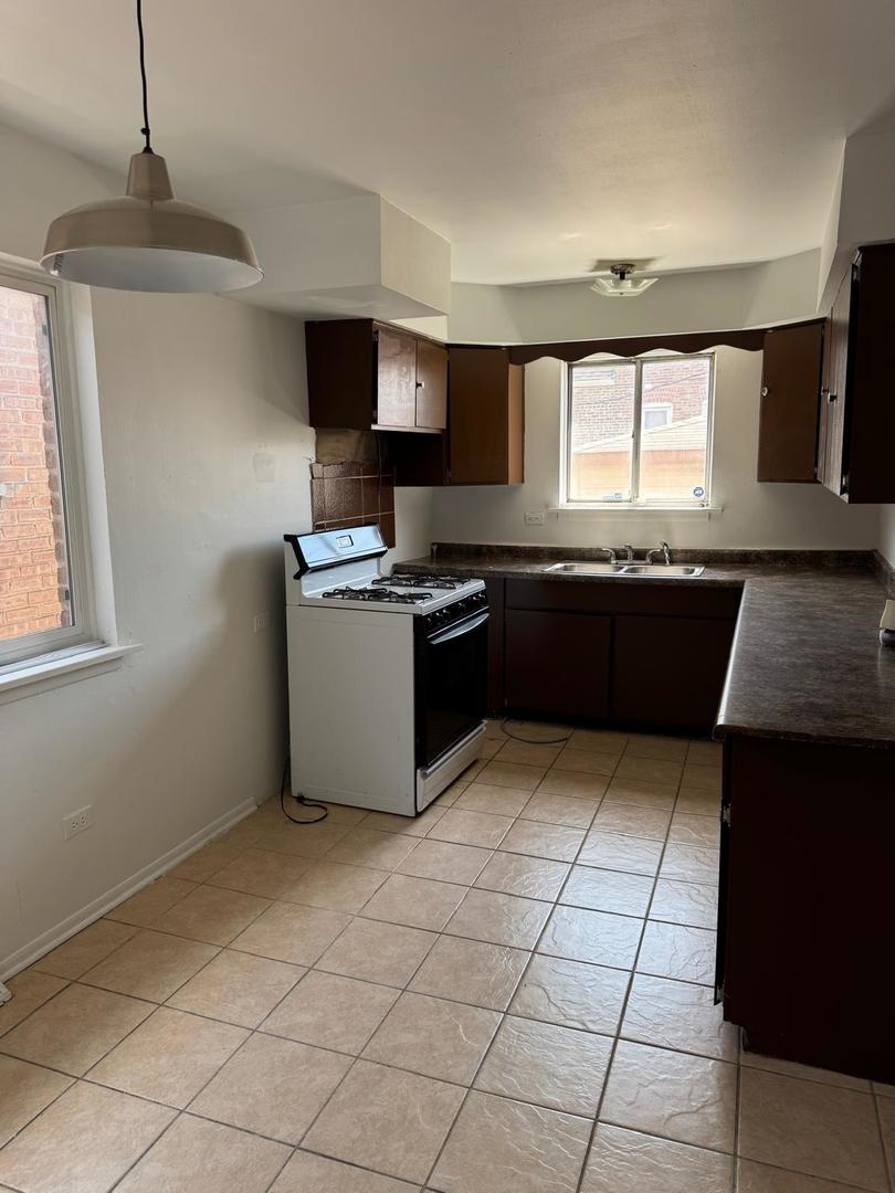 39 West 83rd Street Chicago, IL 60620 - Photo 10 of 12 a kitchen with stainless steel appliances granite countertop a stove a sink and a microwave