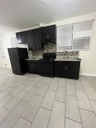 a kitchen with granite countertop a refrigerator and a stove top oven