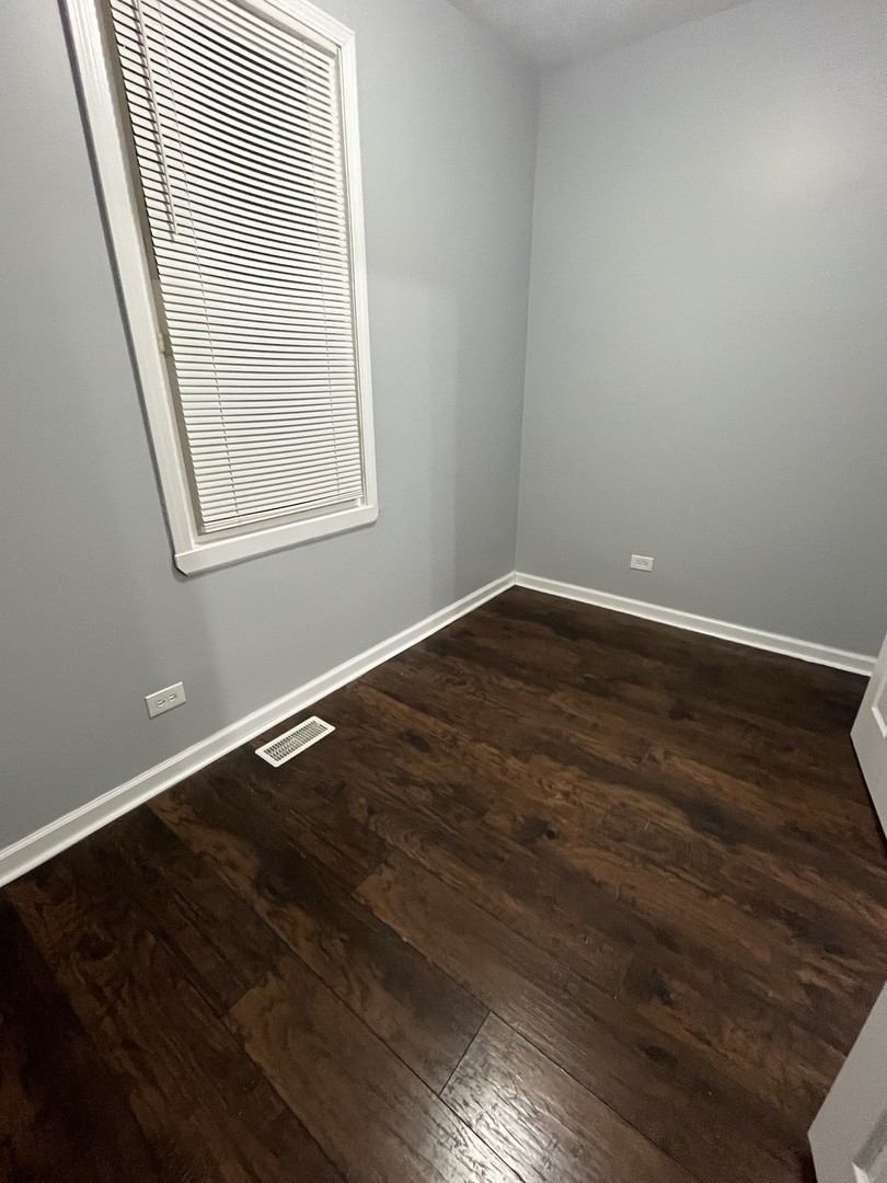 8253 South Brandon Avenue, Unit 1F Chicago, IL 60617 - Photo 6 of 6 an empty room with wooden floor and windows