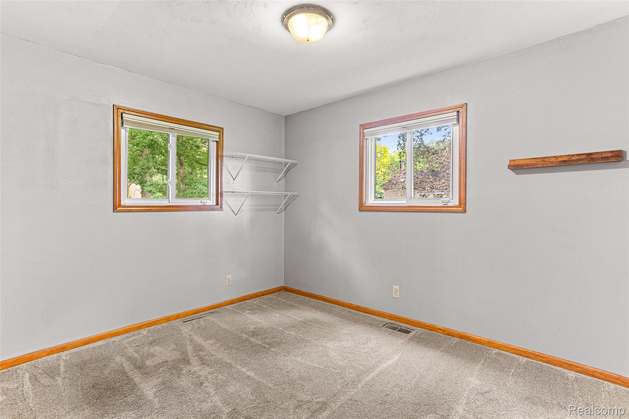 9561 Exeter Road Carleton, MI 48117 - Photo 28 of 46 Neutral gray wall paint with two windows featuring wood-finish trim, a flush-mount ceiling light fixture, and gray carpet flooring