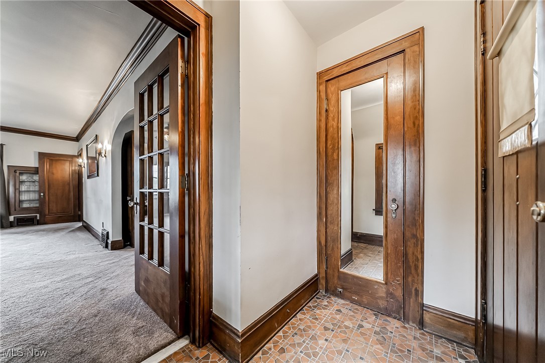 Hallway featuring crown molding, arched walkways, and light carpet