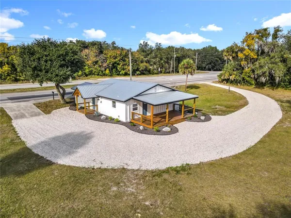 an aerial view of a house with swimming pool and large trees