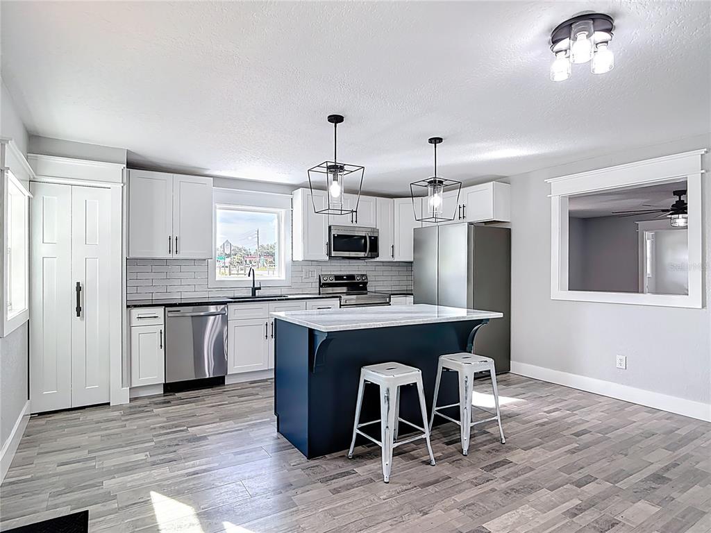379 State Rte 415 Osteen, FL 32764 - Photo 16 of 48 a kitchen with kitchen island granite countertop a sink stainless steel appliances and white cabinets
