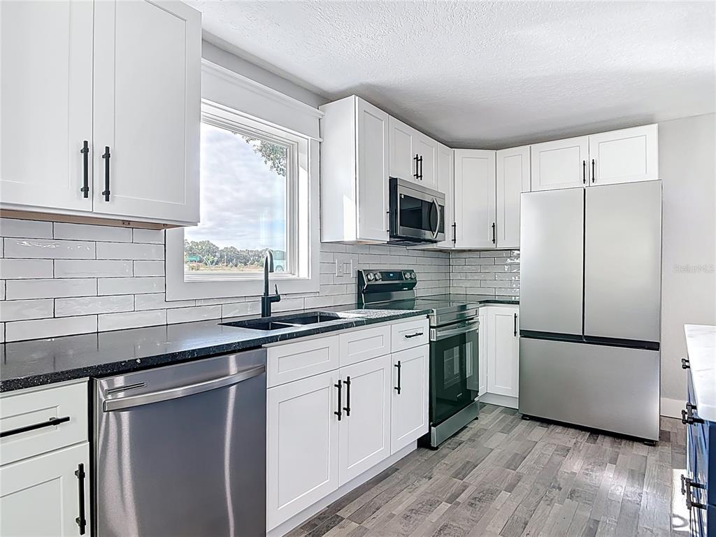 379 State Rte 415 Osteen, FL 32764 - Photo 17 of 48 a kitchen with a sink a refrigerator a window and cabinets