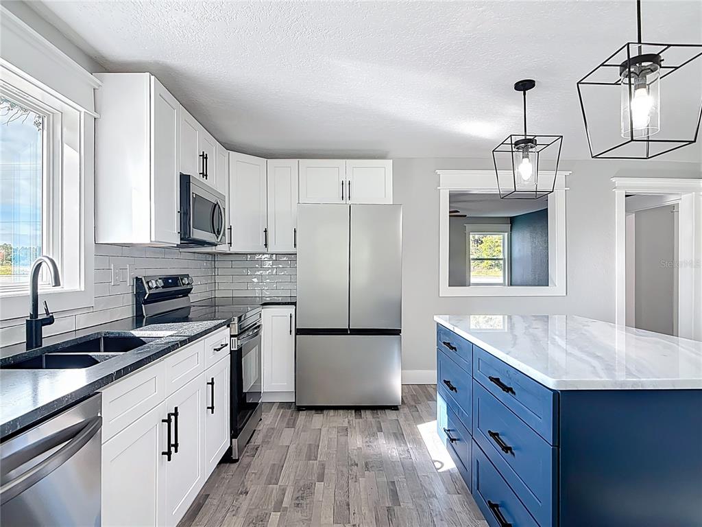379 State Rte 415 Osteen, FL 32764 - Photo 18 of 48 a kitchen with stainless steel appliances granite countertop a sink stove and refrigerator