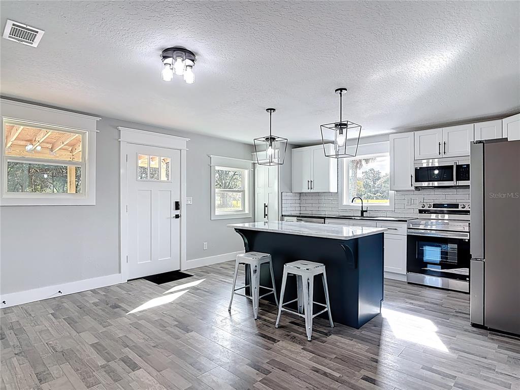 379 State Rte 415 Osteen, FL 32764 - Photo 22 of 48 a kitchen with granite countertop a wooden floor a center island cabinets and stainless steel appliances