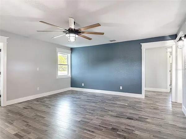 a view of an empty room with window and wooden floor