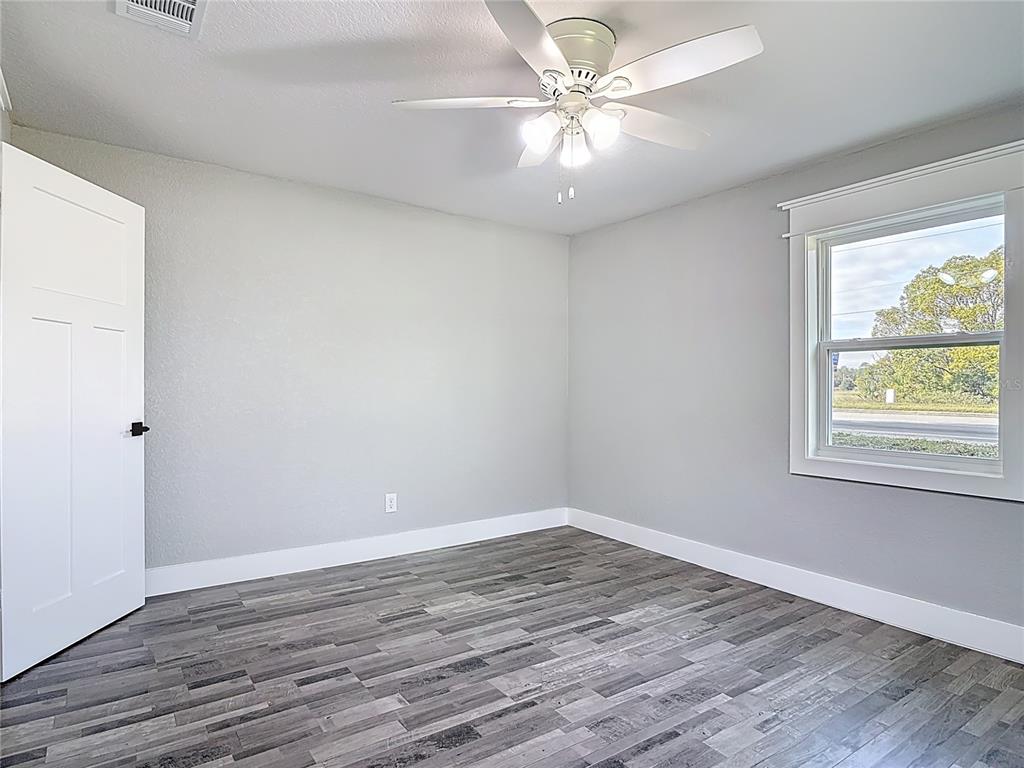 379 State Rte 415 Osteen, FL 32764 - Photo 36 of 48 an empty room with wooden floor chandelier fan and windows