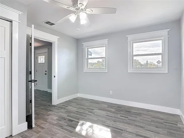 a view of an empty room with wooden floor and a window